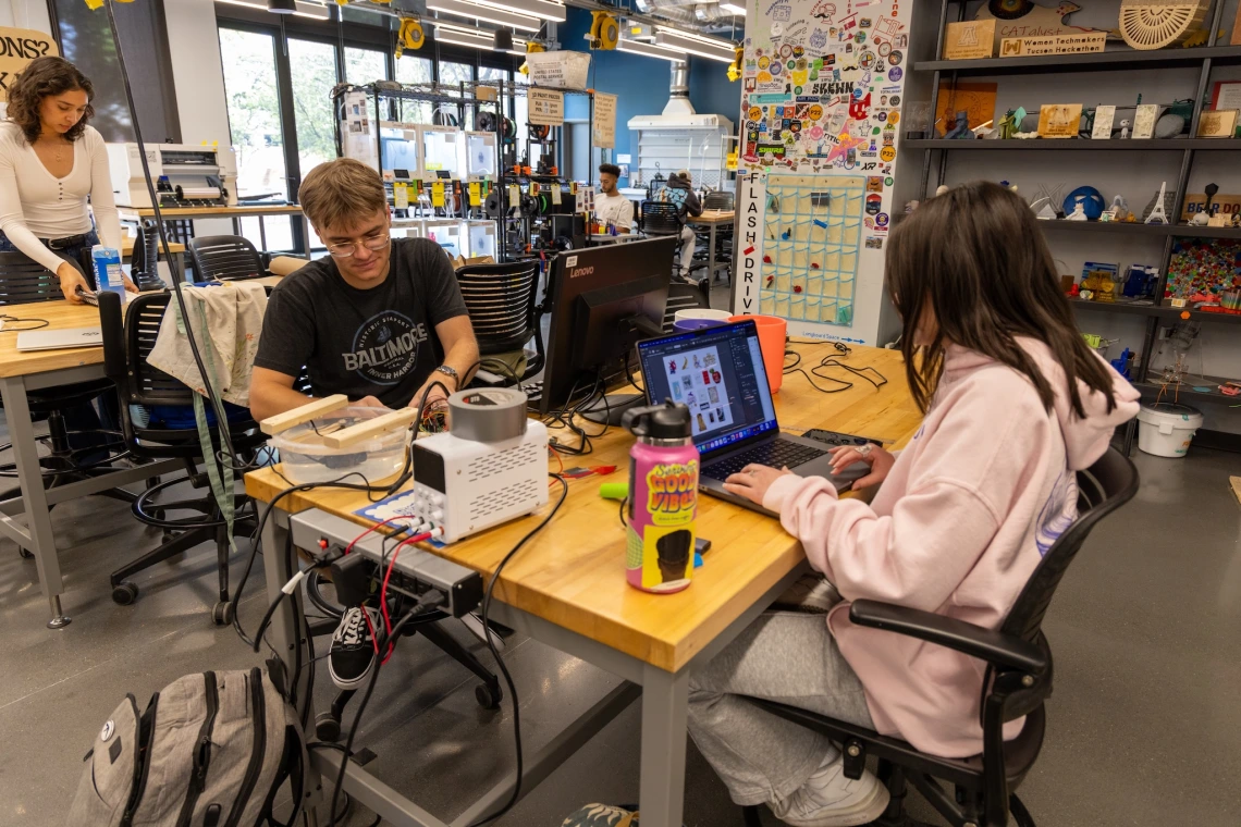 students sitting at tables in maker studio working on projects